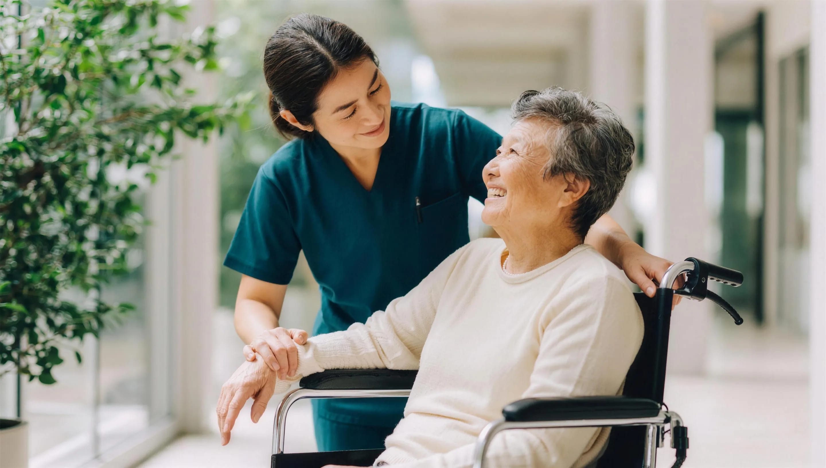 A nurse talking with a smiling elderly patient in a wheelchair
